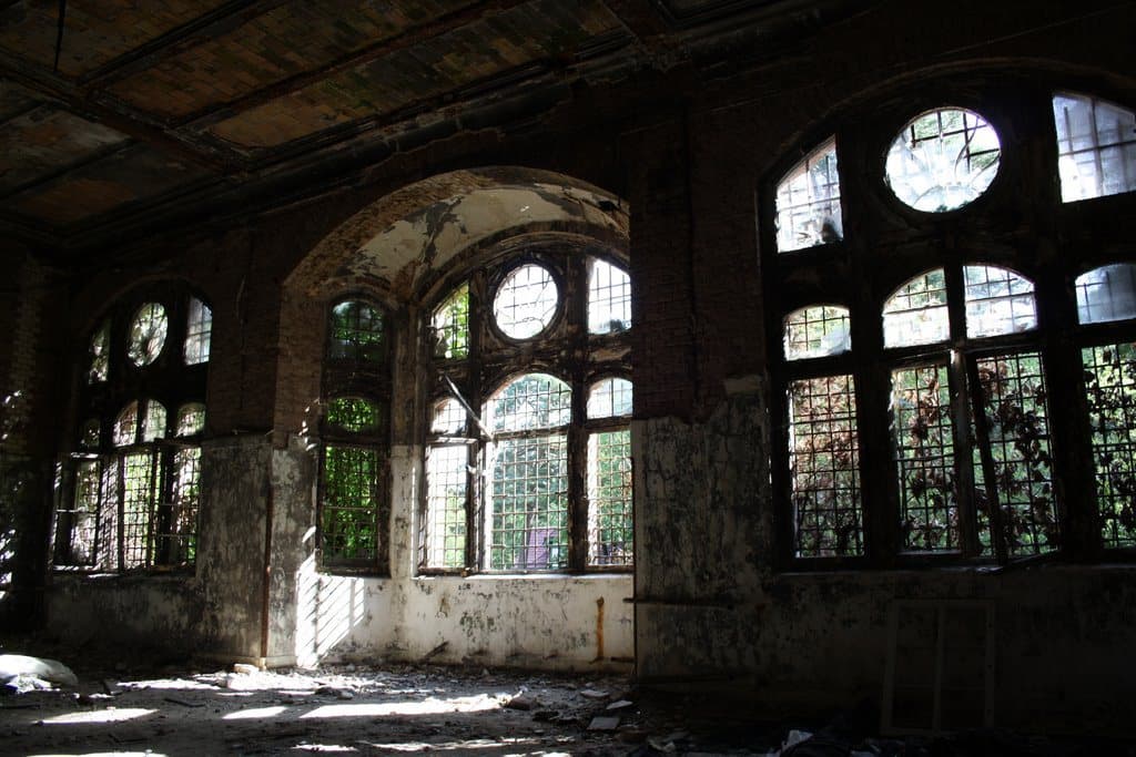 Derelict hall with tall arched and round windows
