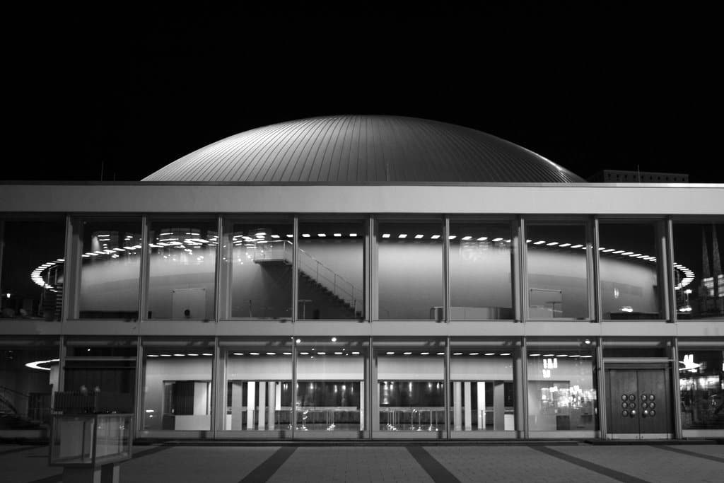 A domed modernist building at night, in black and white