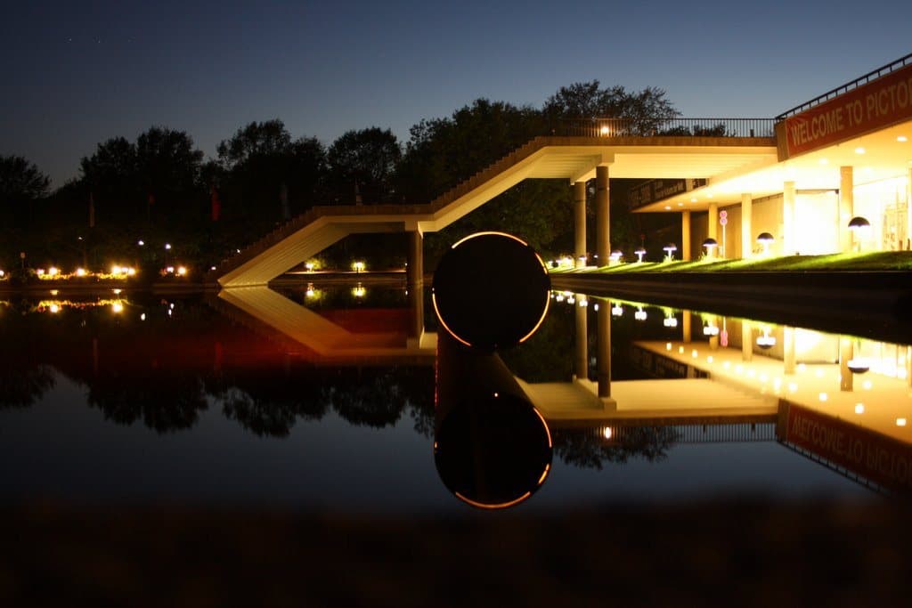 A lit pavilion reflected in still water at night