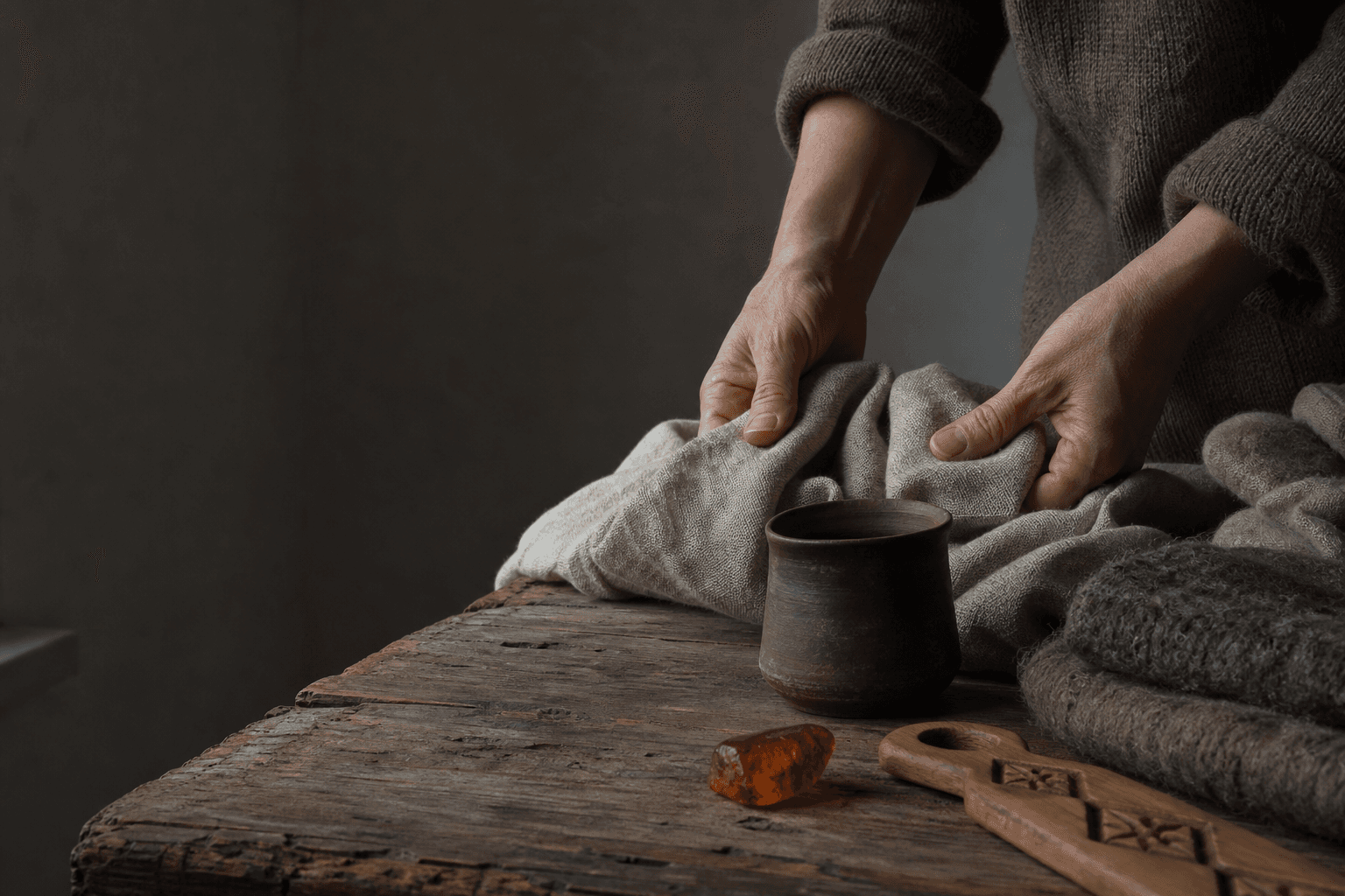 Hands folding linen on a wooden workbench